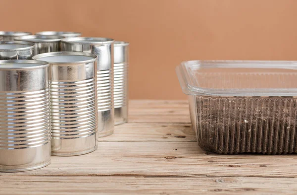 家庭内的创意循环利用 铝罐及花园木制桌子上有泥土的可回收塑料容器 — 图库照片