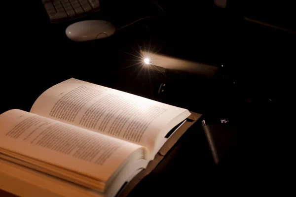 桌上的手机和动力库照亮了以电池驱动的电脑为背景的阅读和学习书籍 照亮了能源贫困概念的停电 — 图库照片