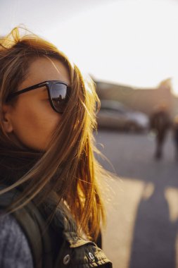 portrait of a young woman, her hair shines beautifully in the sun at sunset, develops and covers her face. a stylish image of a woman. vertical, selective focus clipart