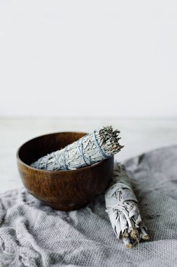 Tahta bir fincanda kurumuş çim beyaz adaçayı kıvırmak. Aromaterapi için bitki ve... Meditasyon aksesuarları. dikey, seçici odak