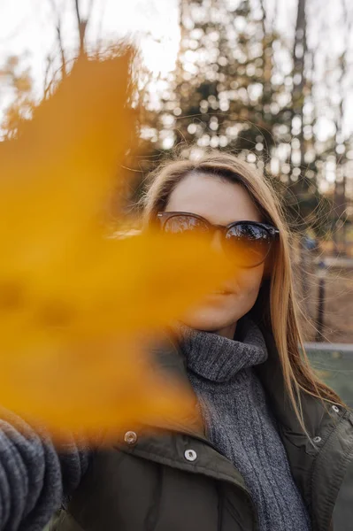 年轻的女人手里拿着黄色的树叶 满脸都是 秋季垂直内容 选择性重点 — 图库照片