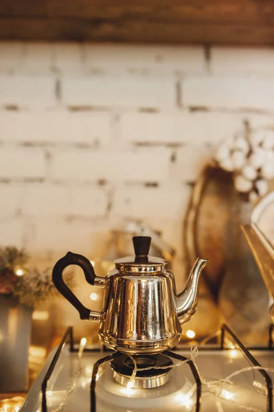 small vintage silver teapot with handle stands on stove and boils. cozy wooden kitchen. Christmas atmosphere. selective focus