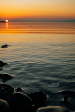 Dağların arka planına karşı denizde inanılmaz ve güzel bir gün batımı. Buzların eridiği ve küçük buzulların yüzdüğü sakin deniz suyu.