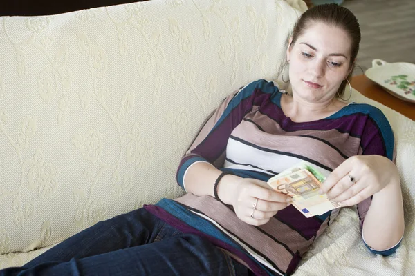 Happy girl with euro on the couch — Stock Photo, Image