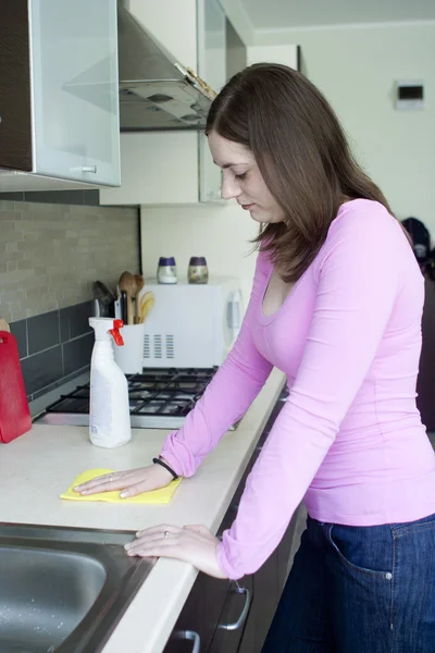 Muchacha atractiva pulido mesa en la cocina — Foto de Stock