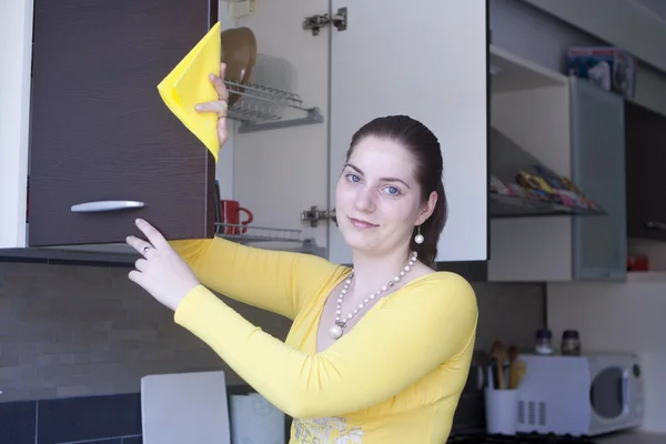 Привлекательная девушка полирует мебель на кухне — стоковое фото