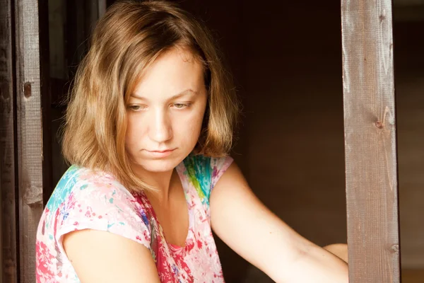 Chica joven sentada cerca de ventana — Foto de Stock