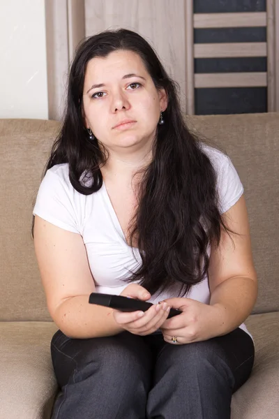 Genç kız evde televizyon izliyor.