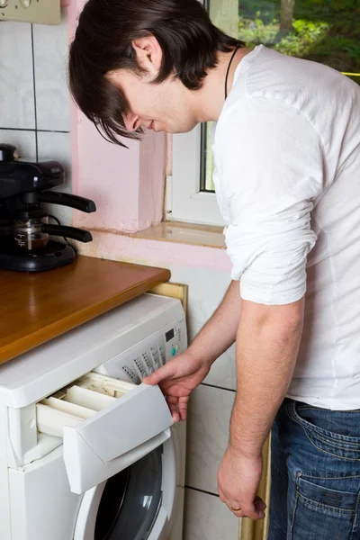 Młody człowiek robi pranie w domu — Zdjęcie stockowe