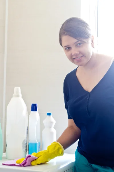 Junge Hausfrau staubt im Badezimmer — Stockfoto