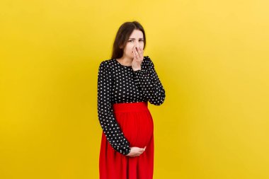 Hamile kadın zehirlenmeden muzdarip. Hamileliğin toksikozu. Renkli bir arka planda duran hamile kadın midesi bulanıyor. Boş Alan.