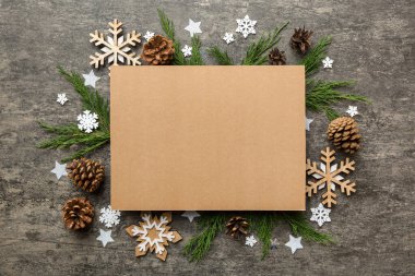 Noel kompozisyonu düzdü. Kare kağıt boş, çam ağacı dalları, renkli arka planda noel süslemeleri. Üst görünüm, metin için boşluk kopyala.