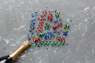 Yaratıcı düz kompozisyon, bir şişe şampanya ve renkli arka plan üzerine yazı için yer. Renkli parti flamalarıyla şampanya şişesi. tatil ya da noel konsepti.