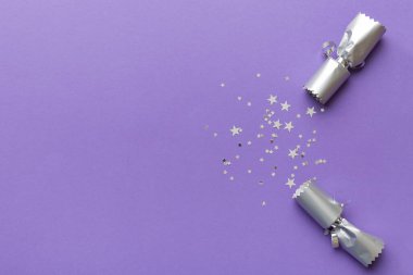 Renkli arka planda parlak konfetileri olan Noel krakerleri, üst görünüm, boşluk kopyala.