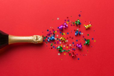 Yaratıcı düz kompozisyon, bir şişe şampanya ve renkli arka plan üzerine yazı için yer. Renkli parti flamalarıyla şampanya şişesi. tatil ya da noel konsepti.