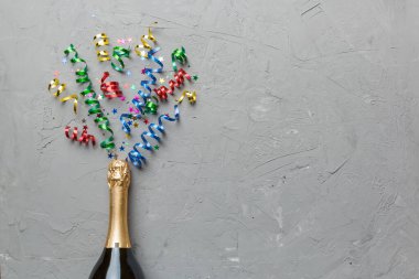 Yaratıcı düz kompozisyon, bir şişe şampanya ve renkli arka plan üzerine yazı için yer. Renkli parti flamalarıyla şampanya şişesi. tatil ya da noel konsepti.