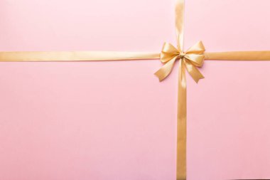 Altın kurdelenin üst görüntüsü yuvarlandı ve sarıyay renkli arka planda izole edildi. Kopyalama alanı olan düz.