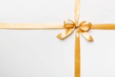 Altın kurdelenin üst görüntüsü yuvarlandı ve sarıyay renkli arka planda izole edildi. Kopyalama alanı olan düz.