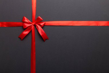 Kırmızı kurdelenin üst görüntüsü yuvarlandı ve kırmızı fiyonk renkli arka planda izole edildi. Kopyalama alanı olan düz.