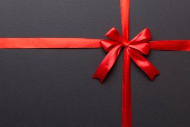 Kırmızı kurdelenin üst görüntüsü yuvarlandı ve kırmızı fiyonk renkli arka planda izole edildi. Kopyalama alanı olan düz.