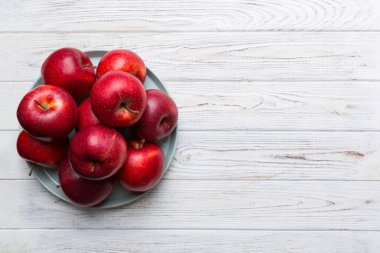 Masanın üstündeki tabakta ya da kasede kırmızı elmalar var. Boşluğu kopyala.