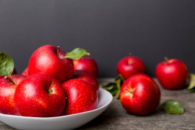 Masanın üstündeki tabakta ya da kasede kırmızı elmalar var. Boşluğu kopyala.
