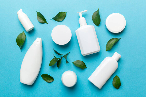 Organic cosmetic products with green leaves on color background. Flat lay.