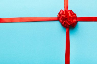 Kırmızı kurdelenin üst görüntüsü yuvarlandı ve kırmızı fiyonk renkli arka planda izole edildi. Kopyalama alanı olan düz.