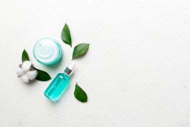 Pamuk çiçekli organik kozmetik ürünler ve çimento arka planında yeşil yapraklar. Uzayı kopyala, düz yat.