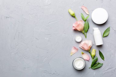 Kozmetik ürünleri ve çimento arka planında güzel güller olan kompozisyon. Uzayı kopyala, düz yat.