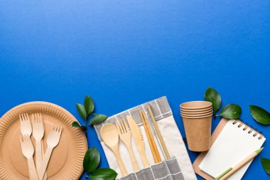 Açık beyaz masa arkaplanındaki boş, tek kullanımlık çevre dostu tabaklar, bardaklar, çatal bıçaklar. Üst Manzara. Biyo-çözünebilir el yapımı yemekler. Geri dönüşüm konsepti. Yakın plan..