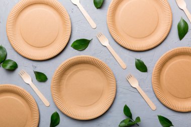 Açık beyaz masa arkaplanındaki boş, tek kullanımlık çevre dostu tabaklar, bardaklar, çatal bıçaklar. Üst Manzara. Biyo-çözünebilir el yapımı yemekler. Geri dönüşüm konsepti. Yakın plan..