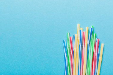 Renkli arka planda renkli plastik pipetler, düz yatış. Metin için Boşluğu Kopyala.