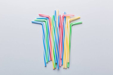 Renkli arka planda parti için pipet içmek. Yaz kokteylleri için renkli plastik tek kullanımlık pipetlerin en üst görüntüsü. kopyalama alanı olan meyve suyu için farklı pipetler.