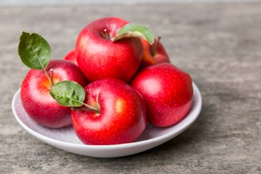 Masanın üstündeki tabakta ya da kasede kırmızı elmalar var. Boşluğu kopyala.