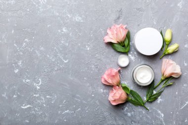 Kozmetik ürünleri ve çimento arka planında güzel güller olan kompozisyon. Uzayı kopyala, düz yat.