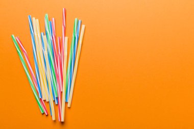 Renkli arka planda renkli plastik pipetler, düz yatış. Metin için Boşluğu Kopyala.