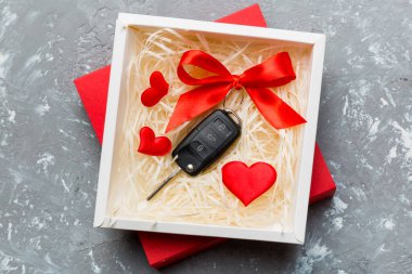 Siyah araba anahtarı, renkli arka planda kırmızı kalp ve kurdele olan hediye kutusunda. Sevgililer Günü Kompozisyonu Üst Görünüm.