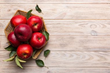 Tahta masada yeşil yapraklı taze kırmızı elmalar. Ahşap arka planda. Metin için üst görünüm boş alanı.