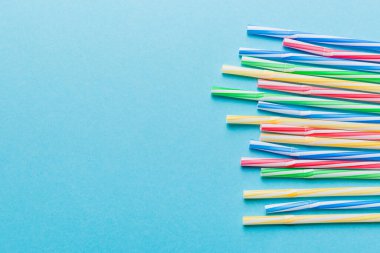 Renkli arka planda renkli plastik pipetler, düz yatış. Metin için Boşluğu Kopyala.