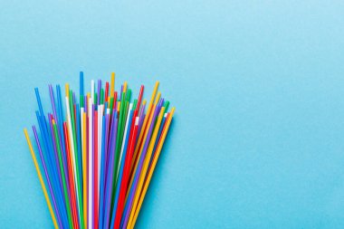 Renkli arka planda renkli plastik pipetler, düz yatış. Metin için Boşluğu Kopyala.