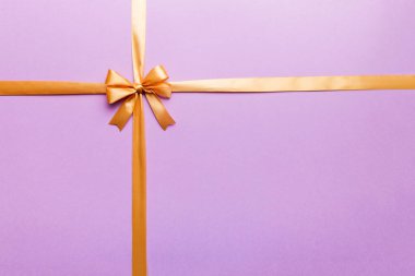 Altın kurdelenin üst görüntüsü yuvarlandı ve sarıyay renkli arka planda izole edildi. Kopyalama alanı olan düz.