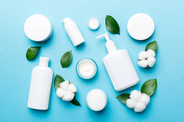 Pamuk çiçekli organik kozmetik ürünler ve ahşap arka planda yeşil yapraklar. Düz yatıyordu.