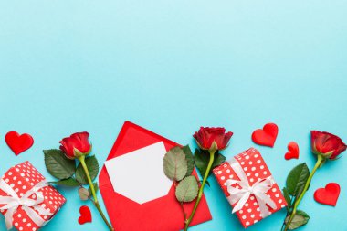 Zarflı sevgililer günü kompozisyonu, gül çiçeği ve kırmızı kalp masada. Üst manzara, düz yatış. Tatil kavramı.