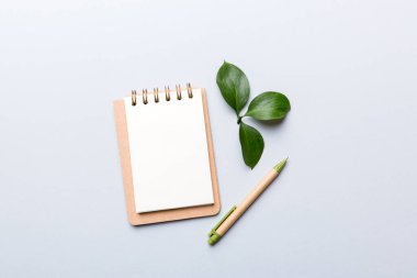 Not için Renkli arkaplan üzerinde kalem ve yeşil yaprak ile çevre dostu boş not defteri.
