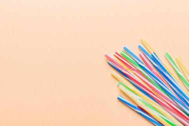 Renkli arka planda renkli plastik pipetler, düz yatış. Metin için Boşluğu Kopyala.