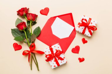 Zarflı sevgililer günü kompozisyonu, gül çiçeği ve kırmızı kalp masada. Üst manzara, düz yatış. Tatil kavramı.