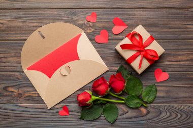 Zarflı sevgililer günü kompozisyonu, gül çiçeği ve kırmızı kalp masada. Üst görünüm, düz görünüm, kopyalama alanı Tatil kavramı.