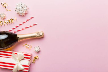 Renkli simli bir şişe şampanya, konfeti ve renkli arka planda metin için hediye kutusu alanı, üst manzara. Komik, noel ve doğum günü kutlaması.