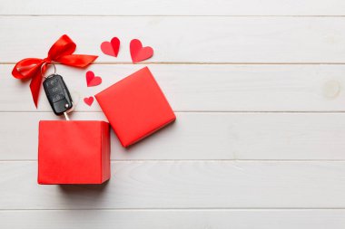 Siyah araba anahtarı, renkli arka planda kırmızı kalp ve kurdele olan hediye kutusunda. Sevgililer Günü Kompozisyonu Üst Görünüm.